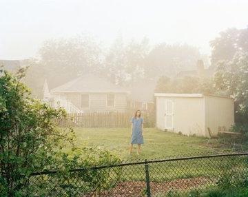 妇女们站在院子里，旁边是白色的房子和棚屋